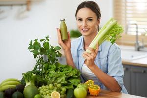 mulher adulta saudável com comida verde na cozinha foto