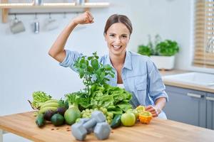 mulher adulta saudável com comida verde na cozinha foto
