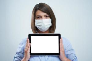 mulher usando máscara protetora e segurando o tablet isolado sobre fundo branco foto