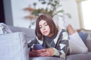 adolescente mandando mensagens de texto em casa foto