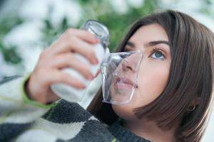 adolescente com um inalador na sala de estar foto