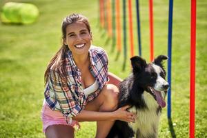 cachorro border collie e uma mulher em um campo de agilidade foto