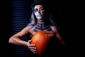 retrato assustador de mulher em maquiagem gótica de halloween segurando abóbora foto