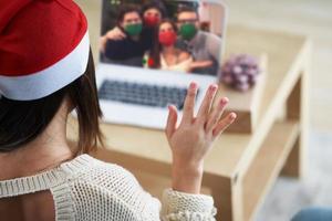 mulher adulta comemorando o natal em casa e fazendo videochamada com amigos foto