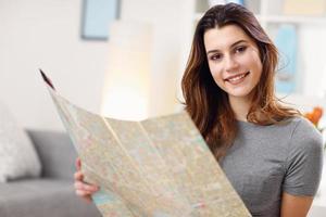 mulher feliz com mapa em casa planejando férias foto