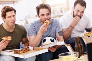 amigos do sexo masculino felizes comendo pizza e assistindo tv foto