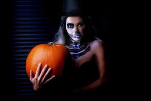retrato assustador de mulher em maquiagem gótica de halloween segurando abóbora foto