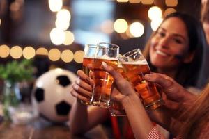 grupo de amigos assistindo futebol no pub foto