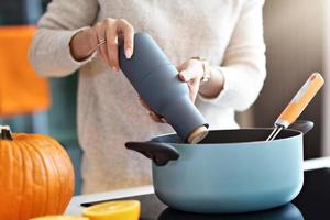 mulher adulta na cozinha preparando pratos de abóbora para o halloween foto