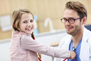 menina na clínica fazendo um check-up com pediatra foto