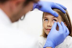 criança optometrista masculino examina a visão da menina foto