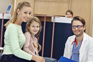 médico acolhendo mãe e filha na clínica foto