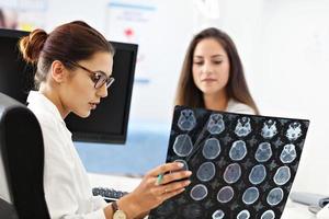 mulher adulta discutindo os resultados do raio-x durante a visita no consultório do médico feminino foto