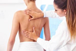 fisioterapeuta feminina ajudando um paciente com problemas nas costas na clínica foto