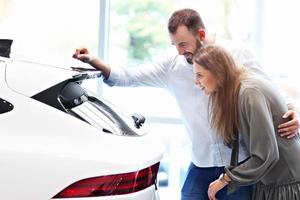 casal adulto escolhendo carro novo no showroom foto