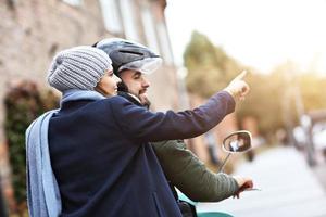 lindo casal jovem sorrindo enquanto andava de scooter na cidade no outono foto