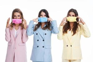 três mulheres em ternos pastel posando sobre fundo branco foto