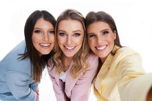 três mulheres em ternos pastel posando sobre fundo branco foto