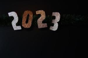 feliz ano novo 2023. números dourados em um fundo preto com glitter foto