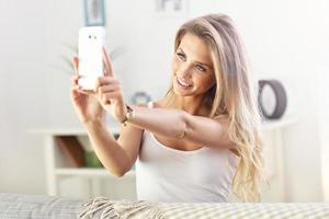 mulher feliz com smartphone no sofá foto