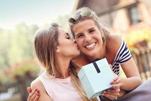 uma foto de duas amigas fazendo um presente de aniversário surpresa