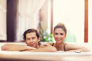 casal feliz desfrutando de jacuzzi no spa do hotel foto