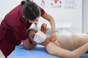 fisioterapeuta em máscara ajudando paciente do sexo feminino foto