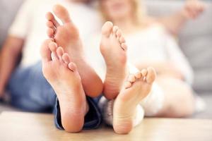 pés descalços de um casal feliz deitado em um sofá foto