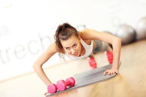 jovem mulher fazendo flexões no ginásio foto