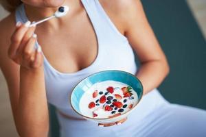 retrato de linda mulher hispânica comendo iogurte promovendo estilo de vida saudável