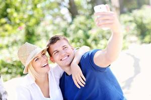 jovem casal tirando uma foto de si mesmos na praia