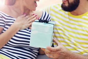 casal feliz com presente sentado do lado de fora foto