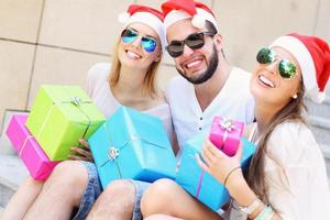 grupo de amigos com chapéus de Papai Noel com presentes foto