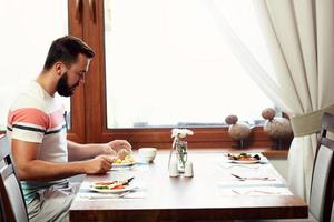 jovem sentado sozinho e tomando café da manhã foto