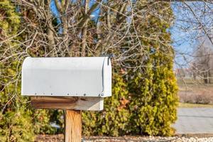 caixa de correio branca ou caixa de correio. linda caixa de correio vintage em um suporte natural, arbustos ao redor. caixa de correio de ferro foto