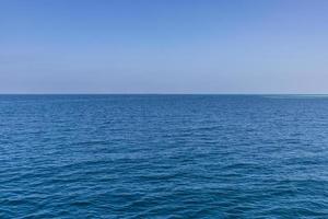 oceano azul ondas horizonte infinito. superfície do mar azul e céu azul claro foto