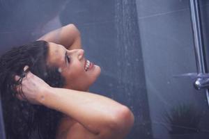 mulher adulta debaixo do chuveiro no banheiro foto