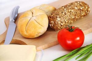 pãezinhos frescos e tomate na tábua foto