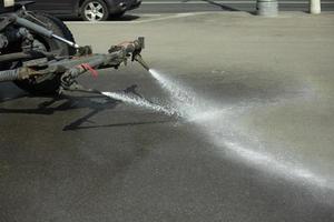 carro lava estrada. trator derrama água. lavando a sujeira do asfalto. jato de água da máquina. foto