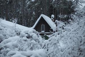 casa na aldeia no inverno. muita neve no telhado da casa velha. foto