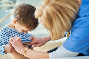 médico pediatra examinando crianças em verificação de orelhas de clínica foto