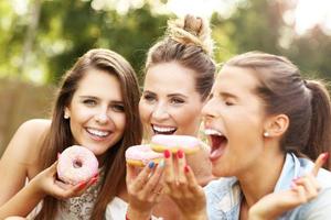 feliz grupo de amigos comendo rosquinhas ao ar livre foto