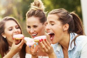 feliz grupo de amigos comendo rosquinhas ao ar livre foto