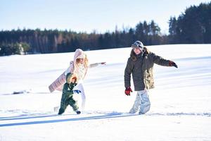 boa família feliz se divertindo na neve do inverno foto