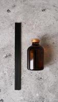 frasco difusor de junco aromático com bastões pretos sobre fundo de mármore escuro. foto