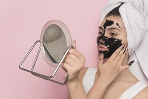 mulher bonita empilhando a máscara preta do rosto. conceito de beleza. isolado foto