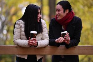 casal misto no parque curtindo um ao outro e bebendo café foto