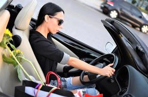 mulher bonita feliz dirigindo um carro esportivo na cidade foto