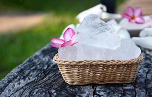 foco suave de cubos de alume e flor de plumeria em pequena cesta de vime, fundo desfocado, conceito de erva, cuidados com o corpo, cuidados com a pele, água limpa, spa, tratamento, proteção contra doenças e proteger o cheiro das axilas. foto