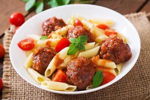 macarrão penne com almôndegas em molho de tomate em uma tigela branca foto